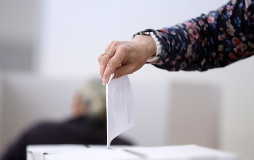 A person dropping their voting paper into the box.
