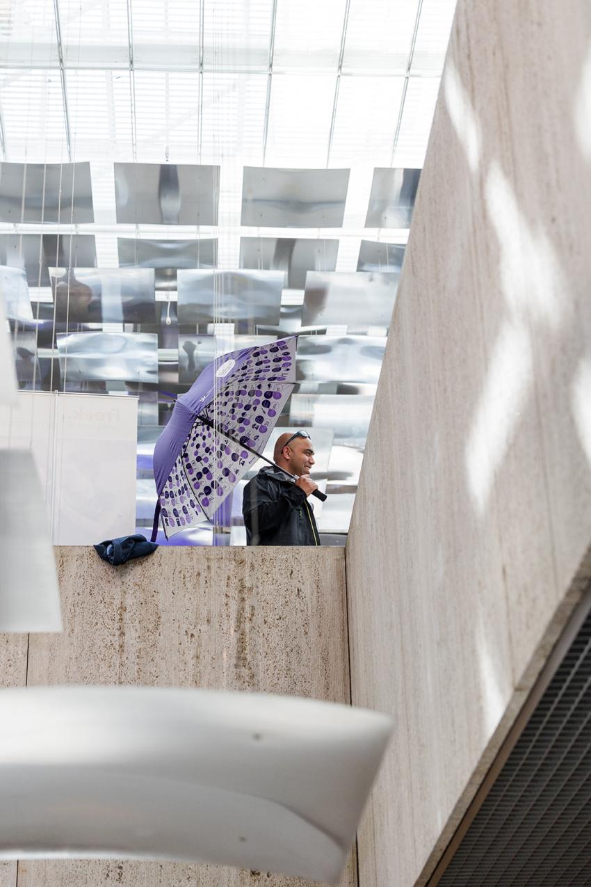 Man holding an open Praat Nederlands met me umbrella