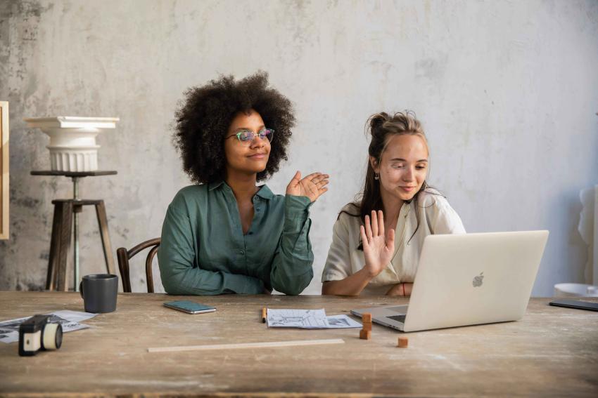 2 women sitting on a call on a laptop