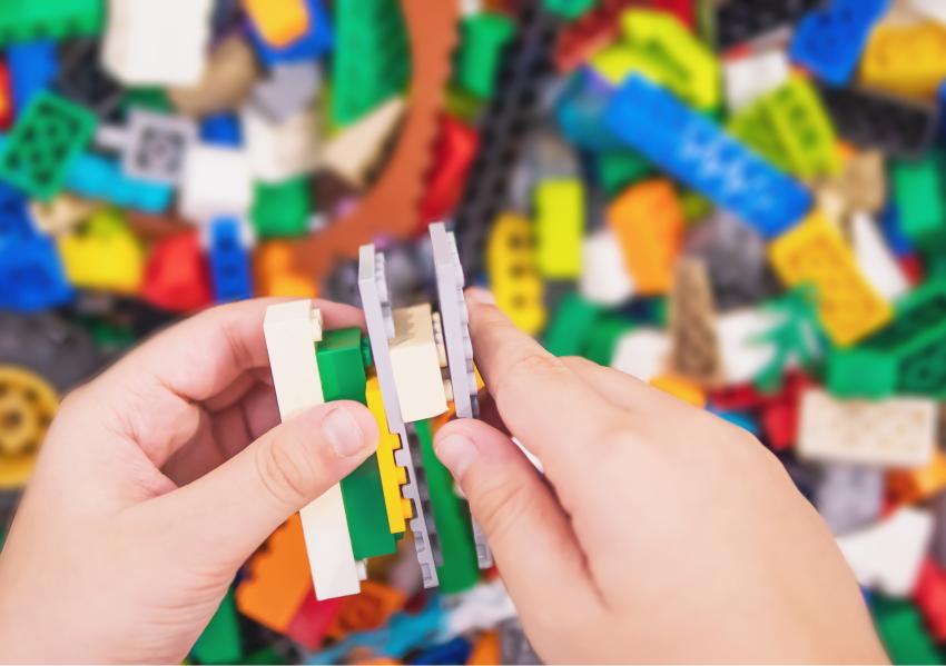 A pair of hands building with multicoloured lego bricks