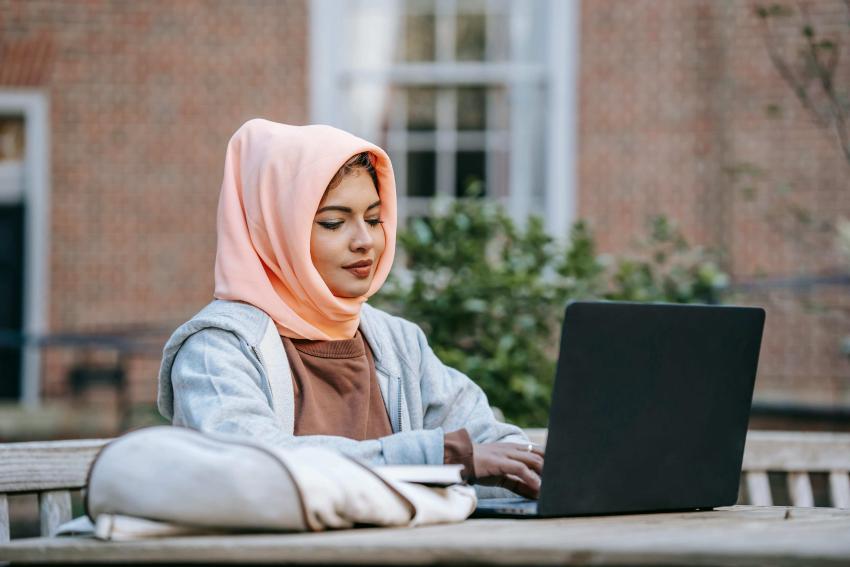 A smiling woman sitting at a laptop