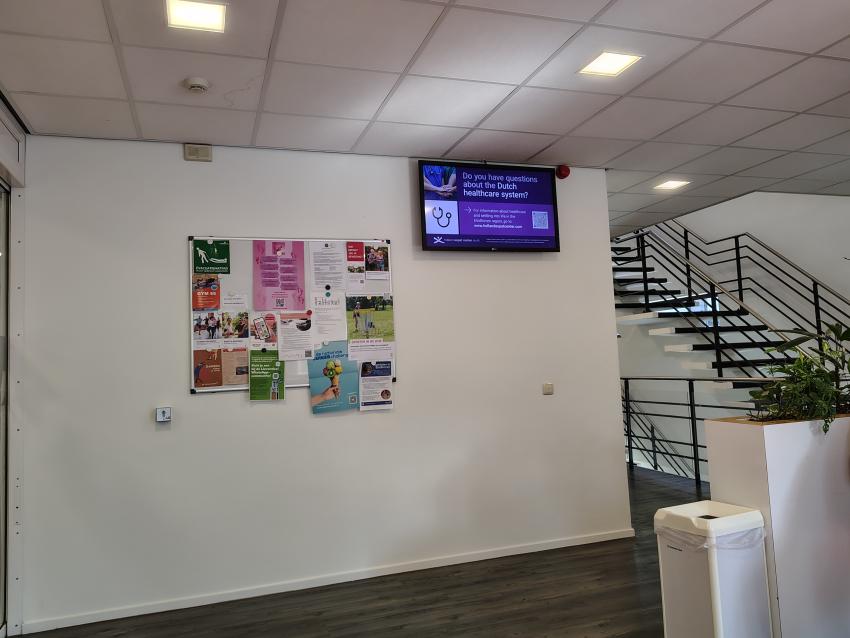 A waiting area with notice board and digital screen