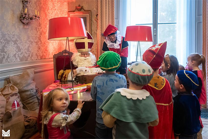 A group of small children gathered around Sinterklaas