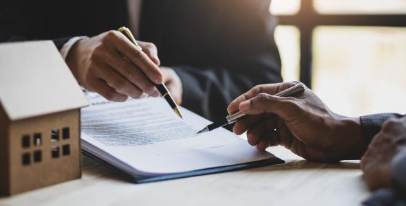 Photo of hands of two people signing a contract