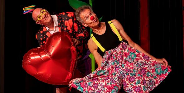 Two people dressed as clowns holding a giant rose