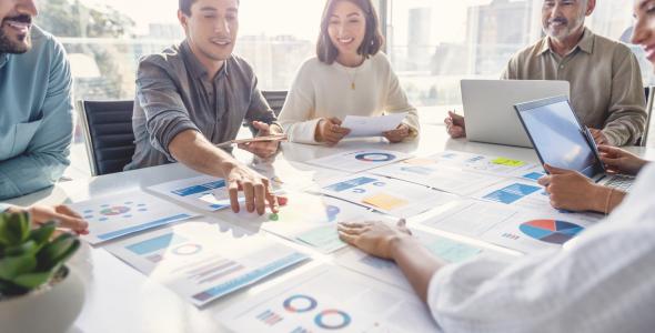 Photo of a meeting with people discussing graphs