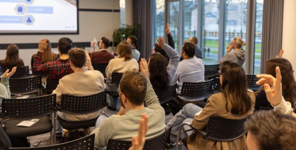 People at a presentation with hands raised