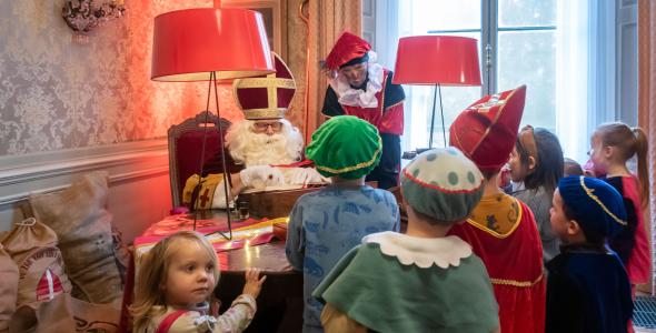 A group of small children gathered around Sinterklaas