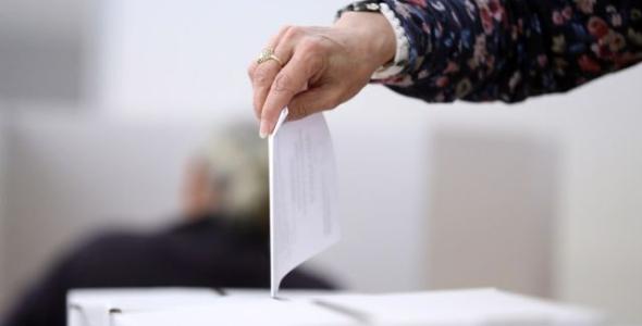 A person dropping their voting paper into the box.