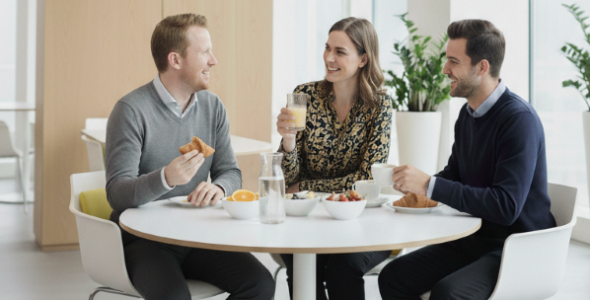 Three smiling people chatting and eating breakfast