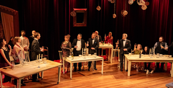 Actors and actresses on stage at a dinner party