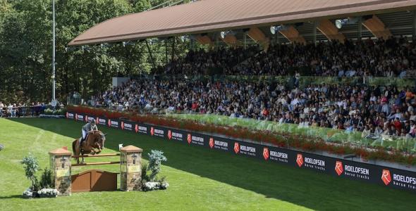 Horse and rider showjumping in an arena with spectators