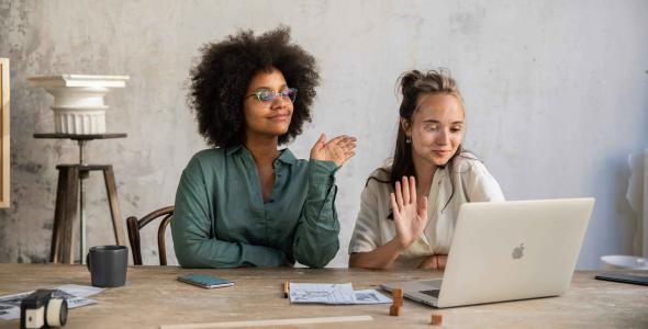 2 women sitting on a call on a laptop