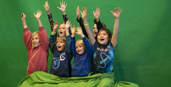 Group of 6 children with hands in the air