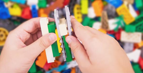 A pair of hands building with multicoloured lego bricks