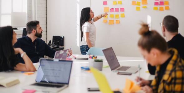 A group of people having a discussion using a whiteboard and sticky notes