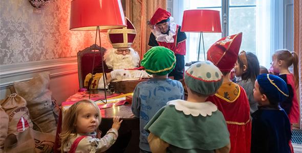 A group of small children gathered around Sinterklaas